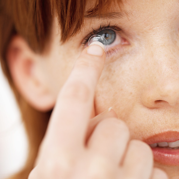 woman inserting contact into eye