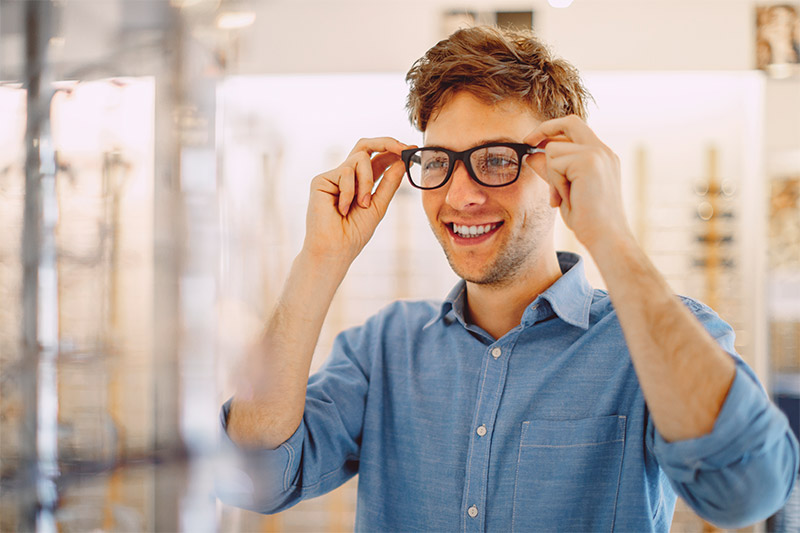 man trying on glasses at eye doctor