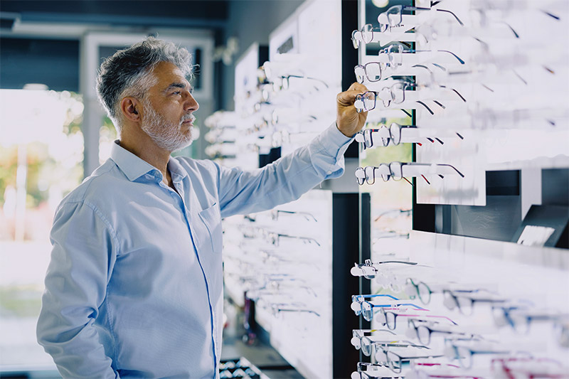man looking at glasses at the eye doctor