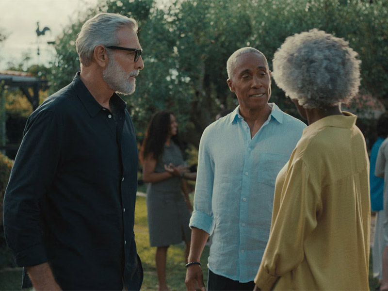 Three adults talking outdoors in a garden setting